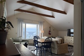 A cozy living room with a dining area, a sofa, a TV, and a guitar. - Expansive Family Home with Water Views (Marion)