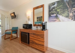 Une pièce comprenant un meuble en bois, une télévision, une machine à café et une chaise.
