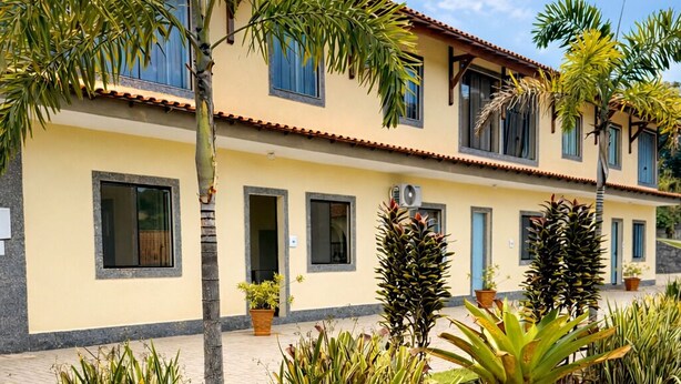 Un edificio de dos plantas con fachada amarilla, varias ventanas y tejado de tejas.