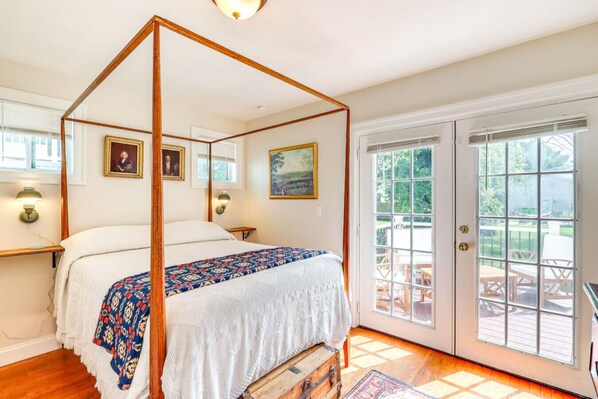 Una cama con dosel con una colcha estampada, un aparador de madera y vistas del patio exterior a través de una puerta de cristal.