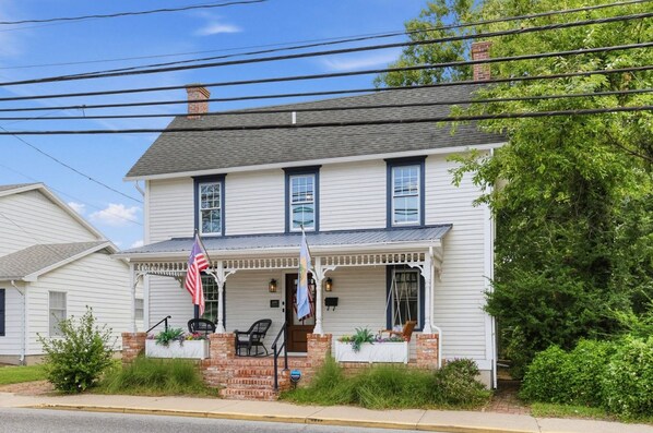 A two-story house with a porch, a flag, and a brick staircase leading to the front door.