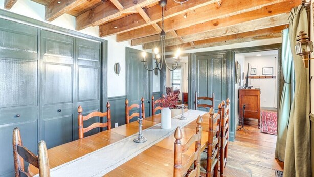 Un espace repas comprenant une longue table en bois, des chaises et un lustre.