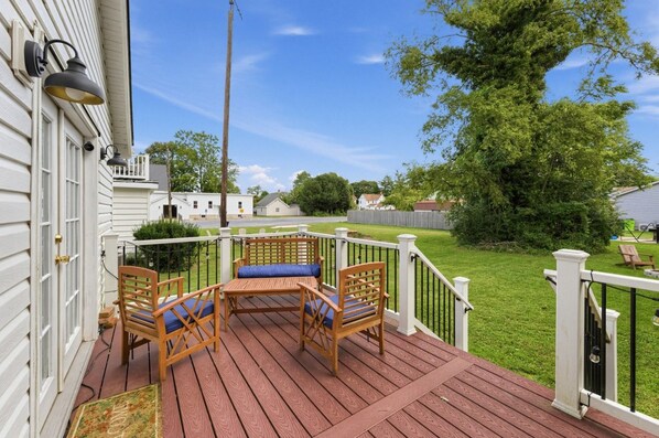 A wooden deck with outdoor furniture, a white railing, and a view of a residential neighborhood.