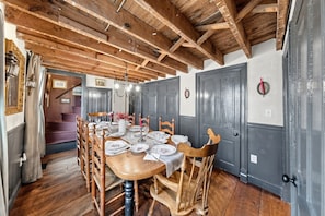 A dining room with a wooden table set for six, surrounded by wooden chairs.