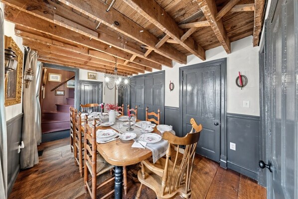 A dining room with a wooden table set for six, surrounded by wooden chairs.
