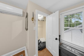 A room with a white door, a window with blinds, and a radiator on the wall.