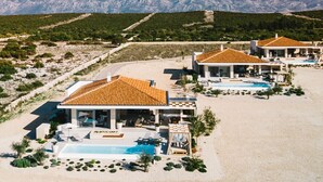 Ett semesterområde med flera villor, där varje villa har en egen pool och utsikt över det omgivande landskapet.