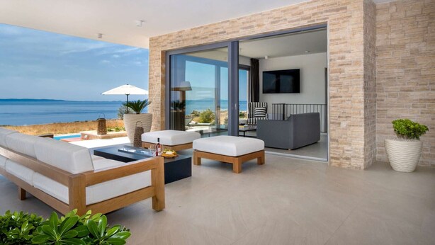 A modern outdoor living area with a sofa, chairs, and a dining table, overlooking a scenic ocean view. - 5* Luxury Seaview Villa Plant 6 with pool (Novalja)