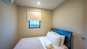 Et hotelværelse med seng, et vindue med udsigt, en aircondition og en dør.