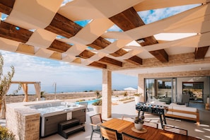 A covered outdoor area with a hot tub, wooden table, and seating, overlooking a pool and a scenic view. - 5* Luxury Seaview Villa Plant 5 with pool (Novalja)