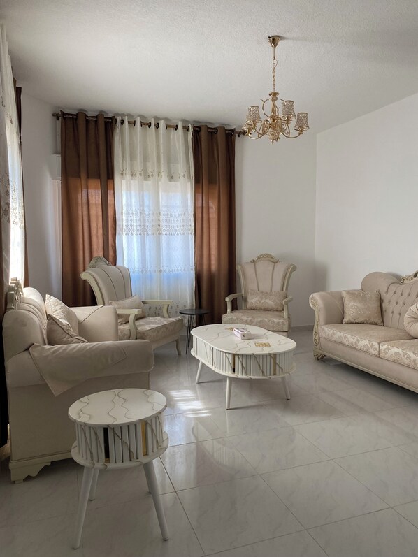 A living room with a sofa, two armchairs, a coffee table, and a chandelier.