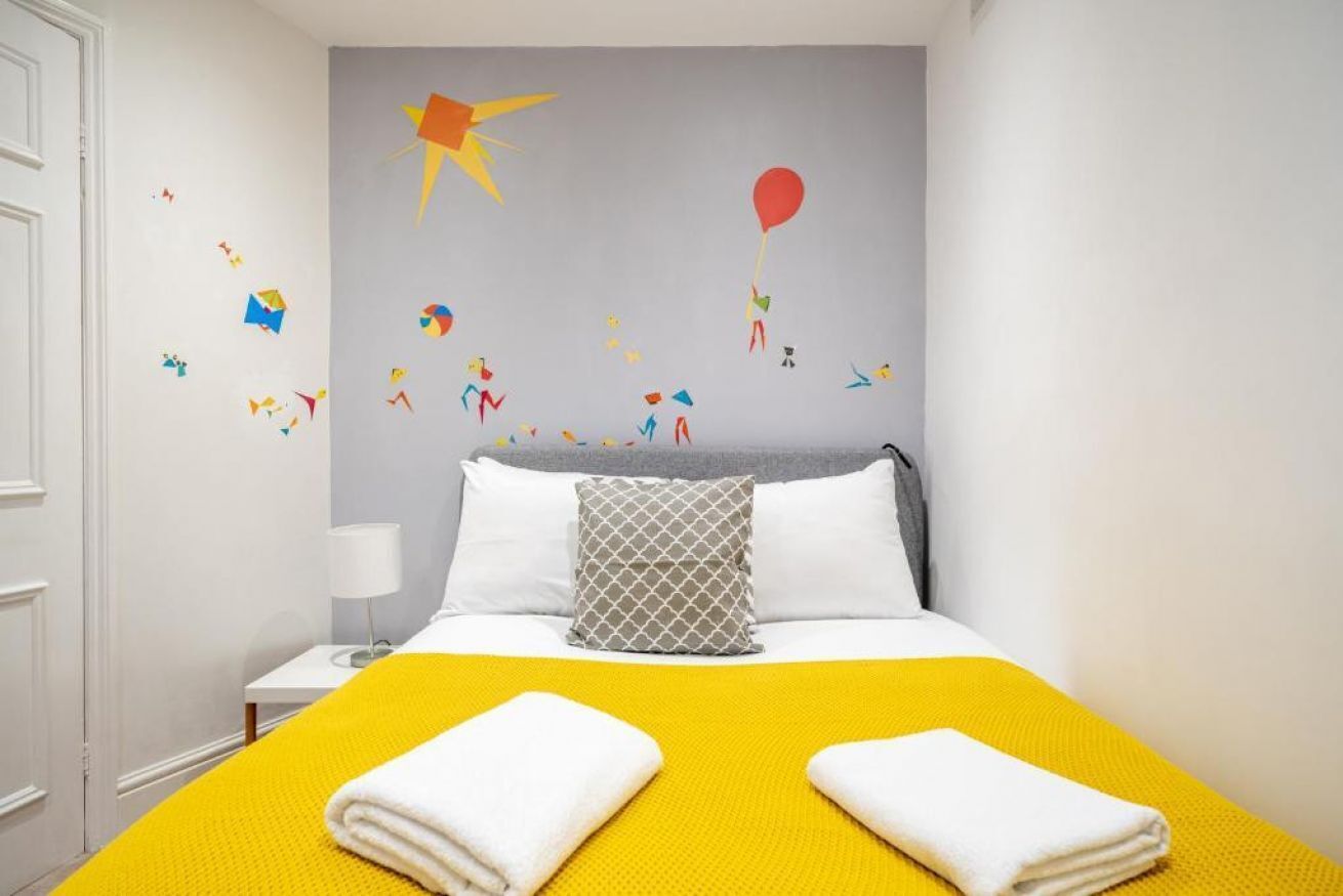 A hotel room with a bed, a nightstand, and a wall with colorful paper decorations.