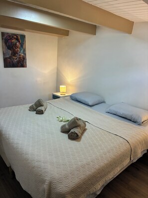 Ein Schlafzimmer mit einem Bett, Kissen, einem Nachttisch mit Lampe und einem Bild an der Wand.