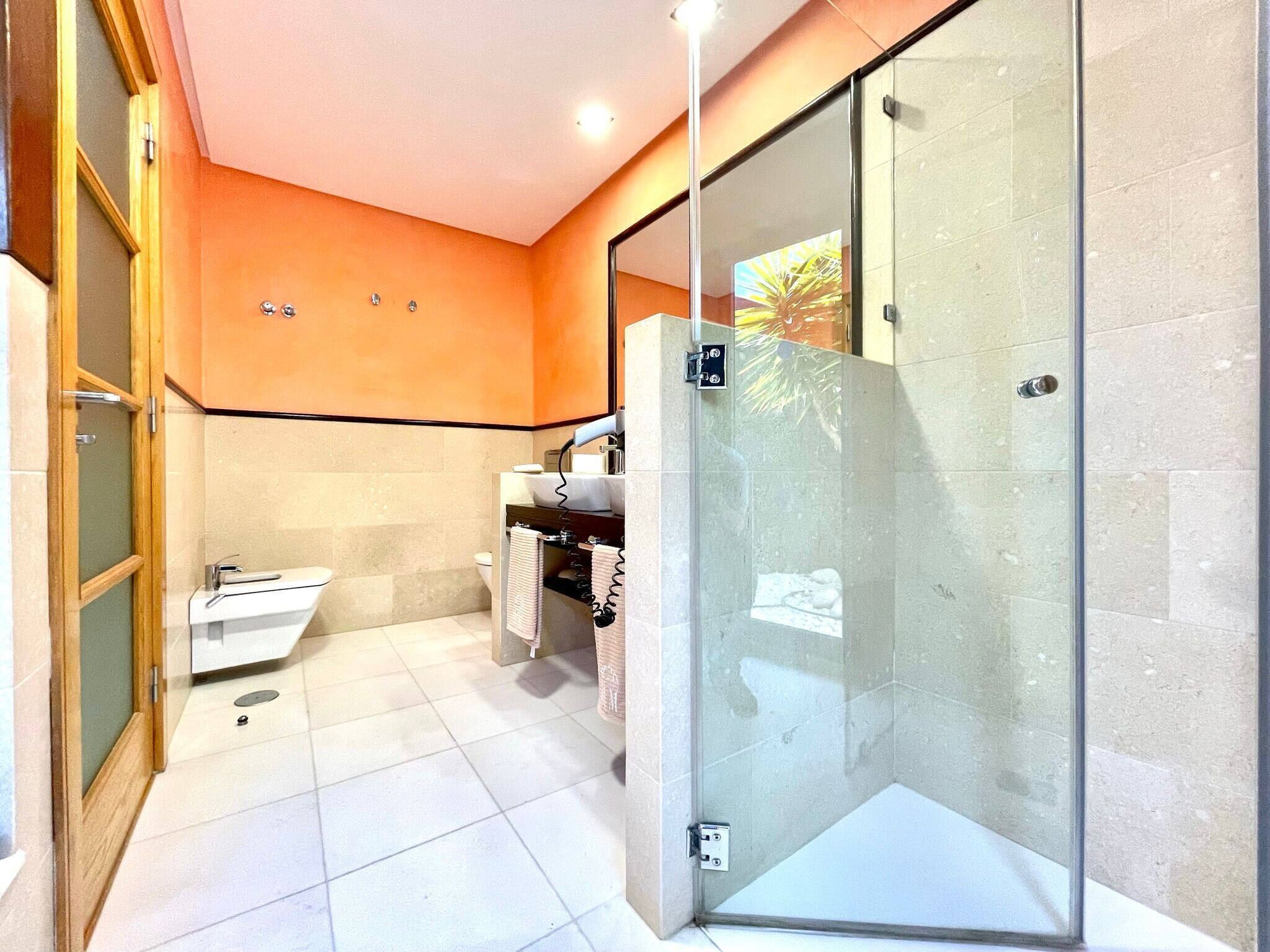 A modern bathroom with a glass shower enclosure, a white sink, and a toilet.