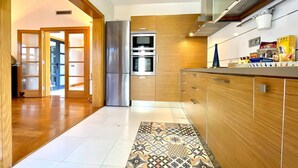 A modern kitchen with wooden cabinets, stainless steel appliances, and a patterned tile floor. - Playas Blanca Pool Private Villas (Yaiza)