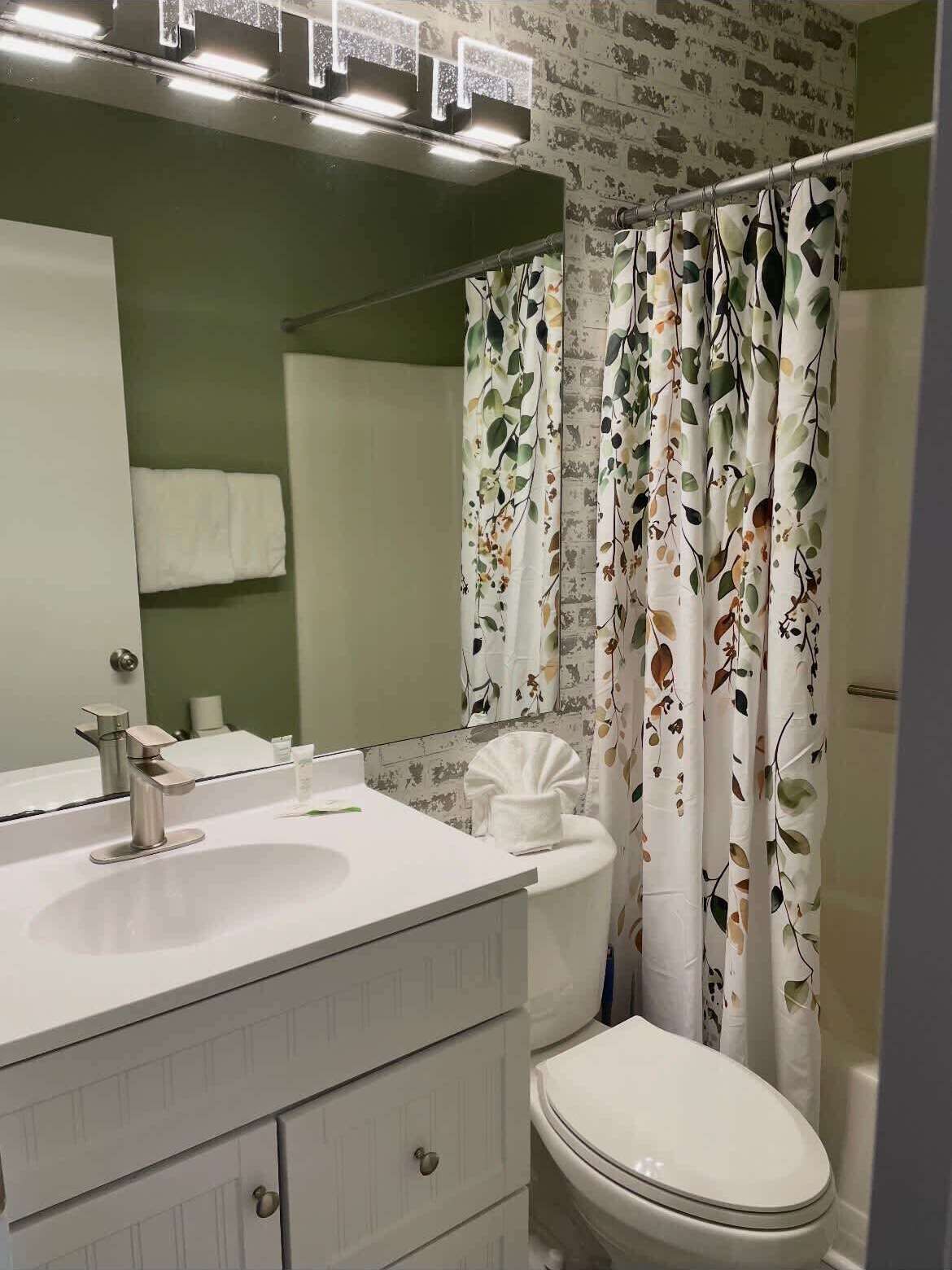 A bathroom with a white sink, mirror, and toilet.