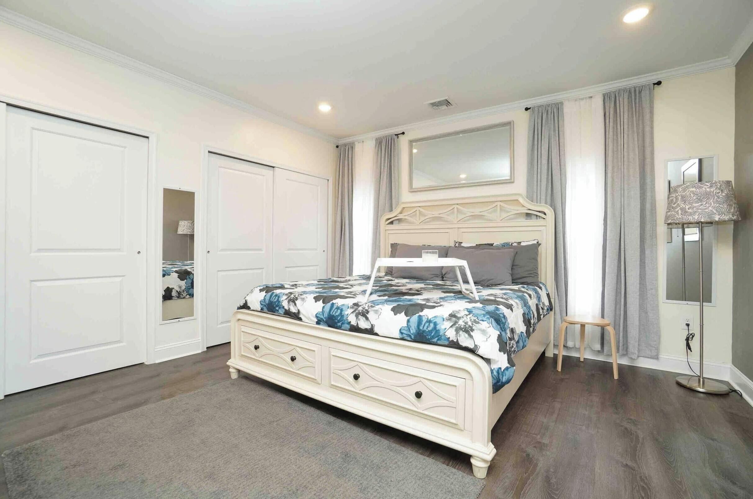 A bedroom with a bed, a dresser, a mirror, and a lamp.
