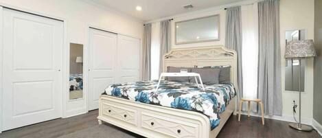 A bedroom with a bed, a dresser, a mirror, and a lamp.