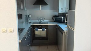 Una cocina compacta con horno integrado, microondas y una campana extractora negra.