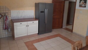 A kitchen with white cabinets, a grey refrigerator, a wooden countertop, and a tiled floor.