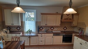 A kitchen with white cabinets, a wooden countertop, and two pendant lights.