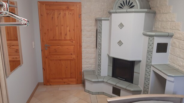 A room with a wooden door, a fireplace with decorative elements, and a tiled floor.
