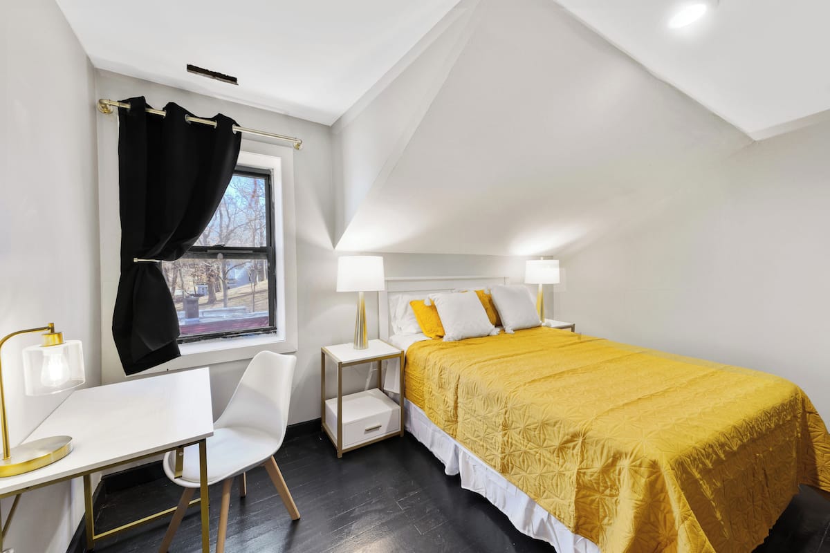A bedroom with a bed, bedside tables, a desk, and a chair.