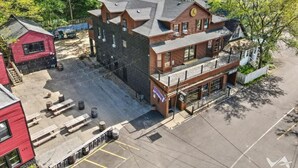 A multi-story building with a prominent clock on the facade, outdoor seating area, and a parking lot. - Randolph Hotel  (Fox Lake)