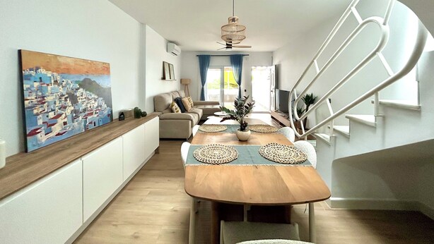 A modern living room with a wooden dining table, a sofa, and a staircase. - Luxury house in MOJÁCAR (Mojácar)