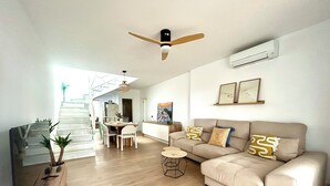 A spacious living room with a beige sofa, a dining table, and a ceiling fan. - Luxury house in MOJÁCAR (Mojácar)