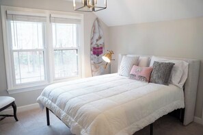 A bedroom with a large bed, a bedside lamp, and a surfboard decoration on the wall. - Stylish 5 bedroom/3b close to HPU, Wyndham & FM! (Jamestown)