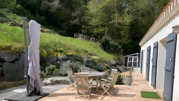 A patio with a table and chairs, a covered bench, and a small shed in a garden setting. - La maison des conches - ref 803 (Longeville-sur-Mer)