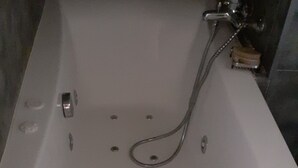 Et badekar med håndbruser og flere afløb.