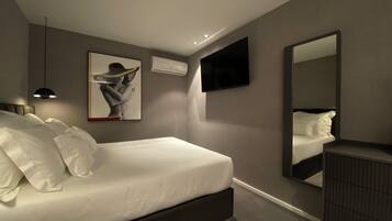 Un dormitorio moderno con cama, televisor de pantalla plana, equipo de aire acondicionado y un cuadro en la pared.