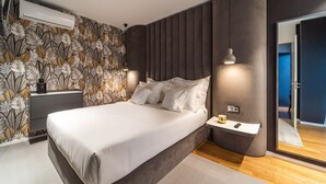 Ein modernes Schlafzimmer mit einem großen Bett, einem Nachttisch, einem Spiegel und einer wandmontierten Klimaanlage.