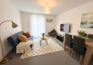 Ein modernes Wohnzimmer mit einer Couch, einem Couchtisch und einem Fernseher.