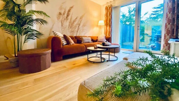 Ein Wohnzimmer mit einer Couch, einem Couchtisch und einem großen Fenster mit Blick auf Grünflächen.