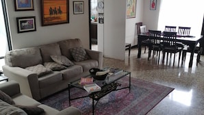 Ein Wohnzimmer mit Sofa, Couchtisch und Essbereich mit Stühlen.
