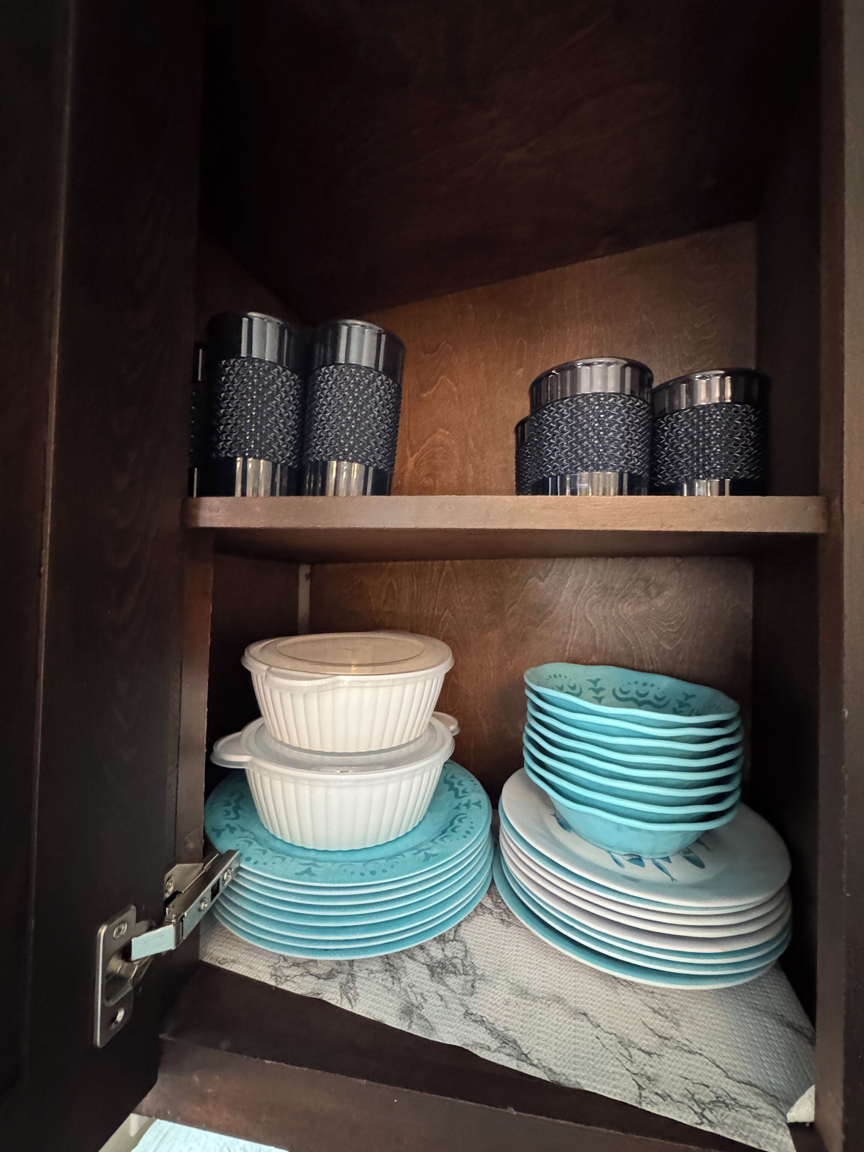 A kitchen cabinet with shelves holding various kitchenware items.