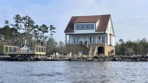 Une maison à deux étages avec un quai, un espace abrité et une terrasse en bois.