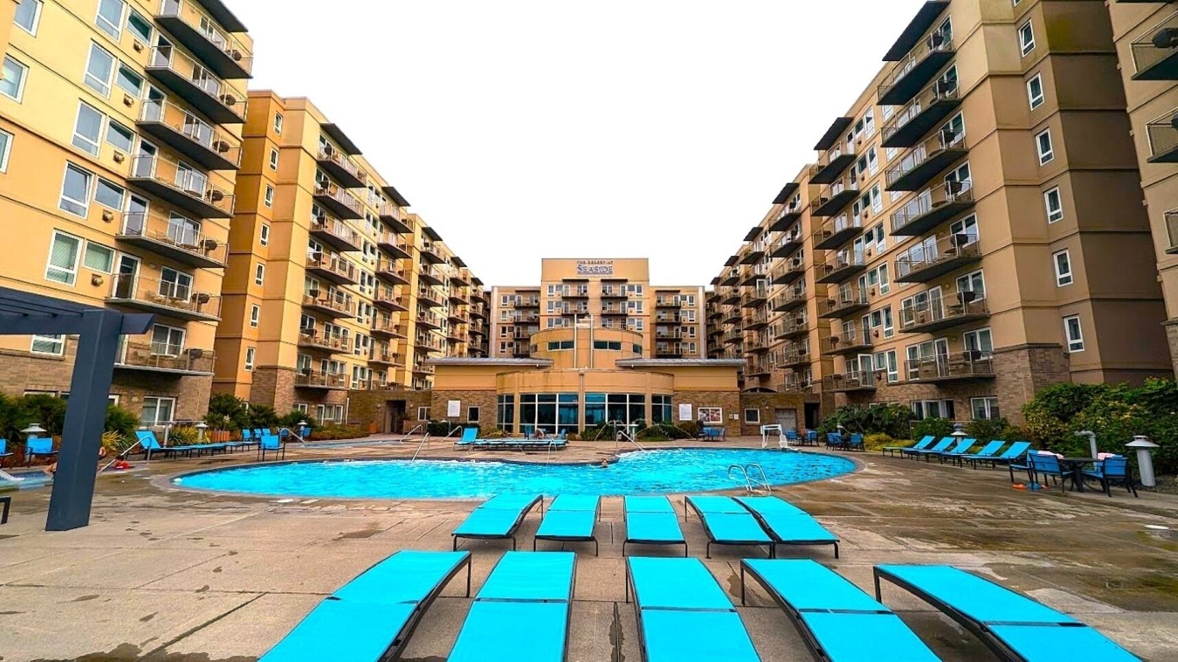 Un edificio residencial de varios pisos con un patio central que cuenta con una piscina y tumbonas.