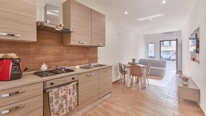 Una cocina moderna con estufa a gas, cafetera y comedor con mesa y sillas.