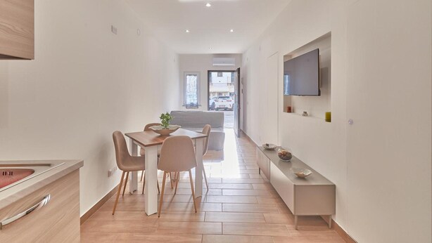 Cocina moderna con comedor, televisor en la pared y vista a la calle.