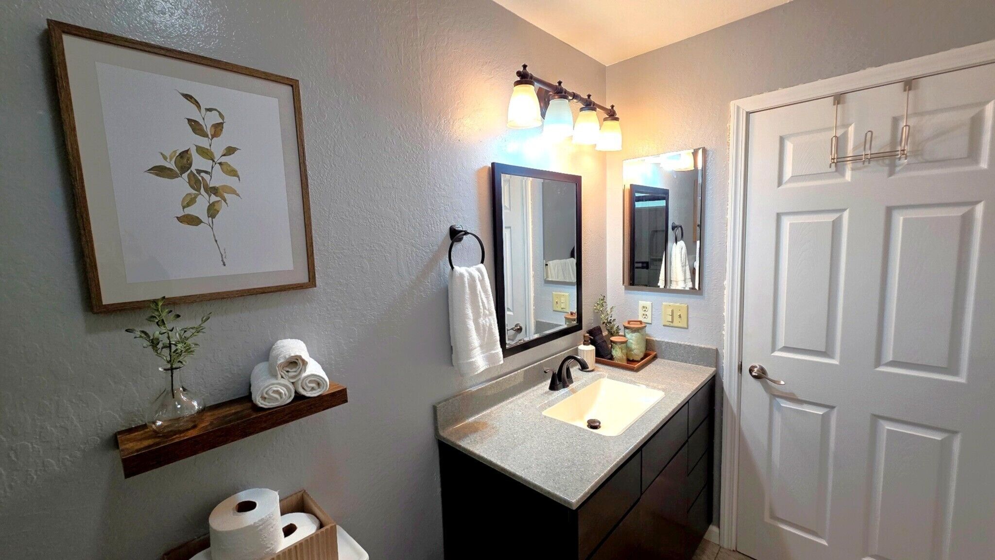 A bathroom with a sink, mirror, towel rack, and framed artwork.