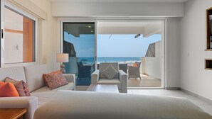 A modern hotel room with a large bed, a sofa, and a chair. There is a sliding glass door leading to a balcony with a view of the ocean. - 1-bedroom Ocean view Condo in Vivo Resorts, Puerto Escondido, Gym & Tennis Court (Bajos de Chila)