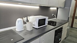 A modern kitchen with a microwave, kettle, and utensil holder on the counter. - Como lecco lake apartments (Malgratemalgrate)