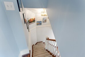 A staircase with a wooden handrail, white walls, and a light fixture. - Historic Downtown Charleston: 2BR/2.5BA with Rooftop Terrace & Parking (Charleston)