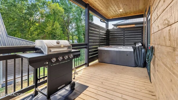 A covered outdoor deck with a grill and a hot tub. - Cozy Fall Retreat*Near Dollywood/Island*HotTub*Xbox (Pigeon Forge)