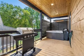 A covered outdoor deck with a grill and a hot tub. - Cozy Fall Retreat*Near Dollywood/Island*HotTub*Xbox (Pigeon Forge)