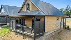 A modern house with a sloped roof, a covered porch, and a fenced yard. - Cozy Fall Retreat*Near Dollywood/Island*HotTub*Xbox (Pigeon Forge)